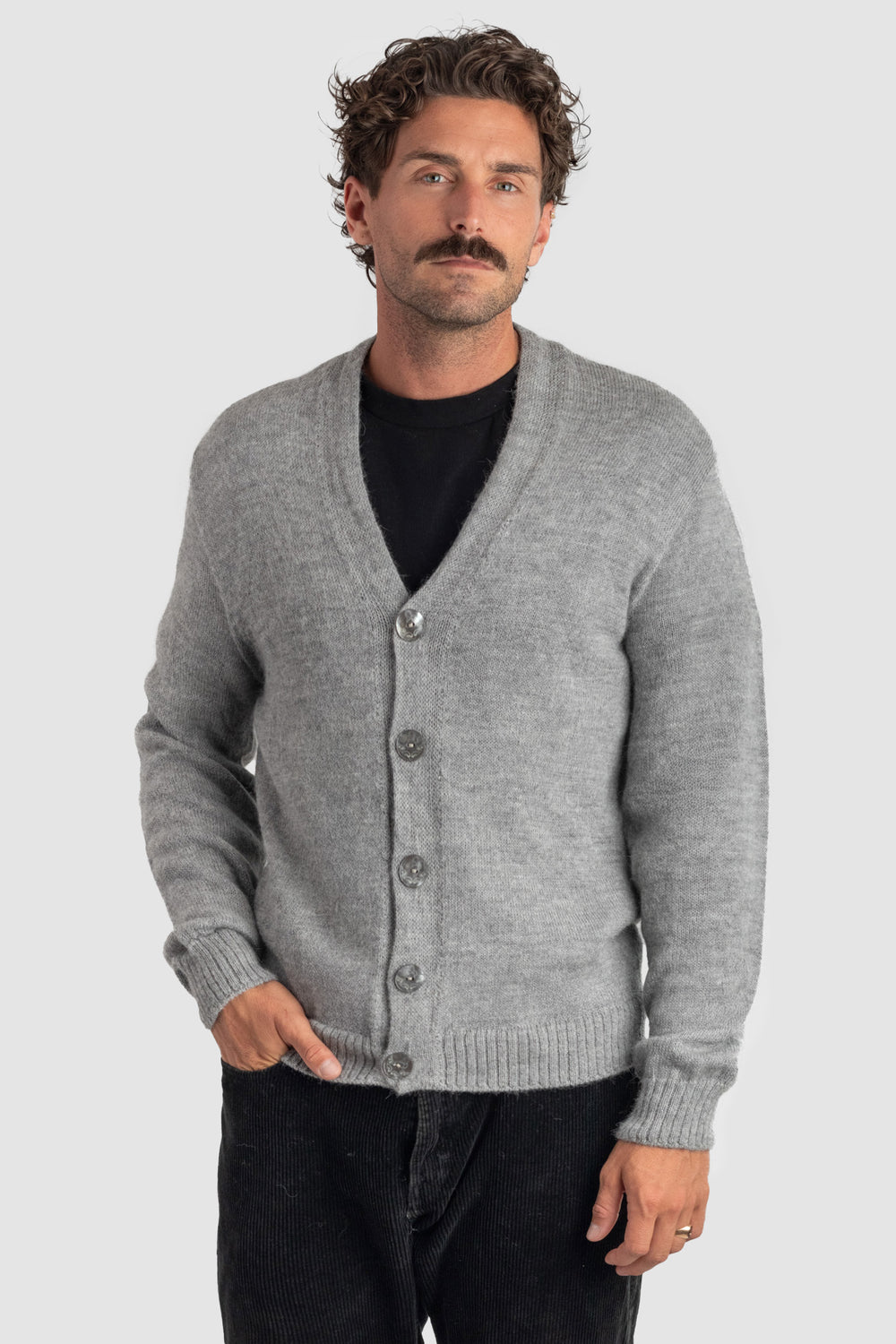 Man wearing a gray cardigan over a black shirt on a light gray background #colour_cool-grey